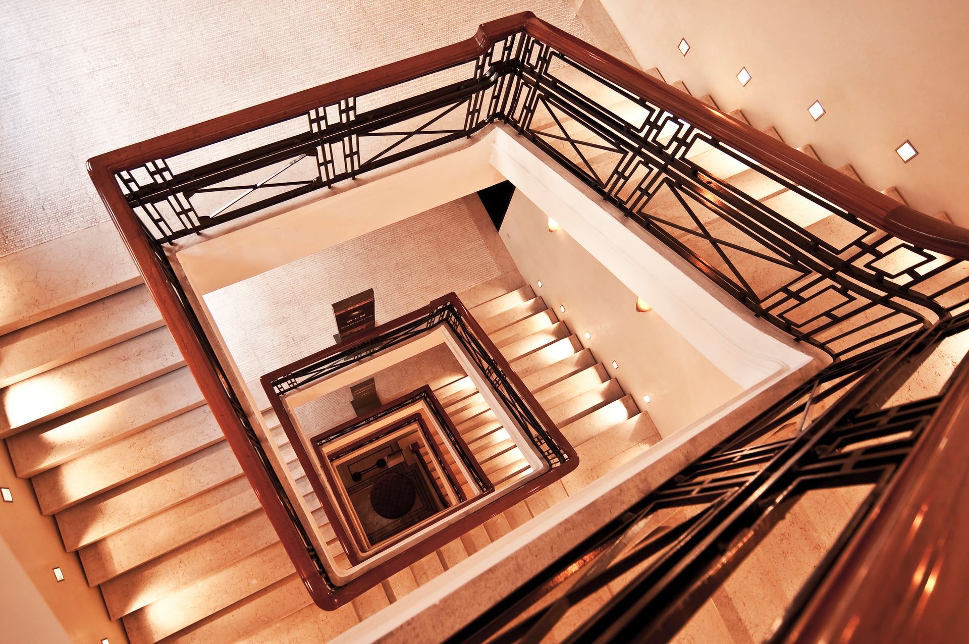 Escalier vu du dessus, forme rectangulaire, rampes et balustres en bois, marches couleur crème, éclairage naturel.