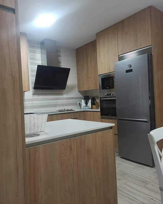 Una cocina con gabinetes de madera y refrigerador de acero inoxidable.
