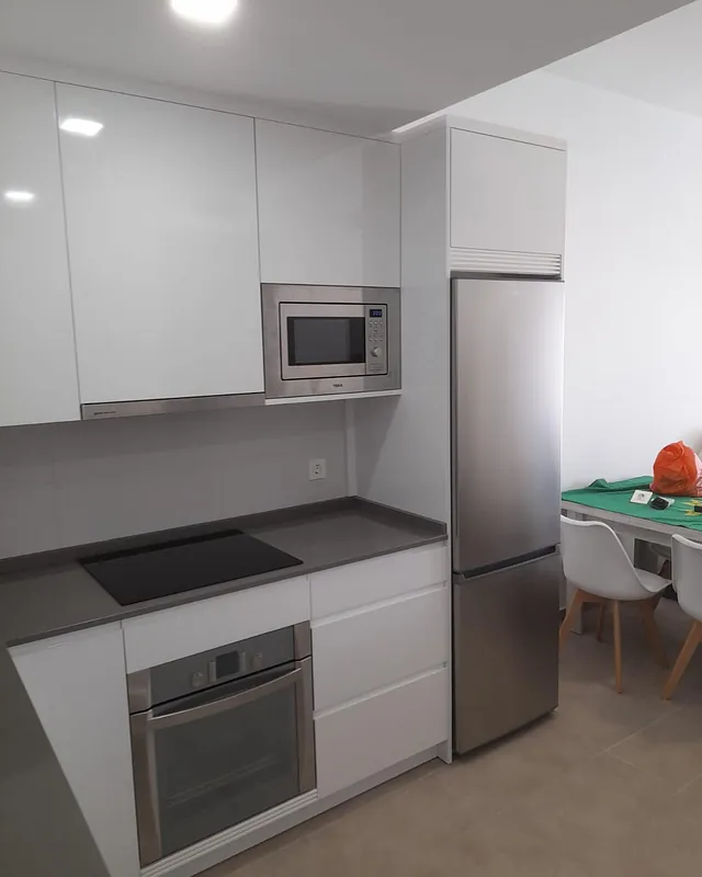 Una cocina con electrodomésticos de acero inoxidable y gabinetes blancos.