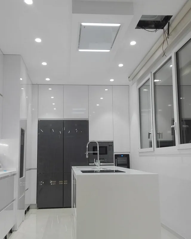 Una cocina con gabinetes blancos y un ventilador de techo.