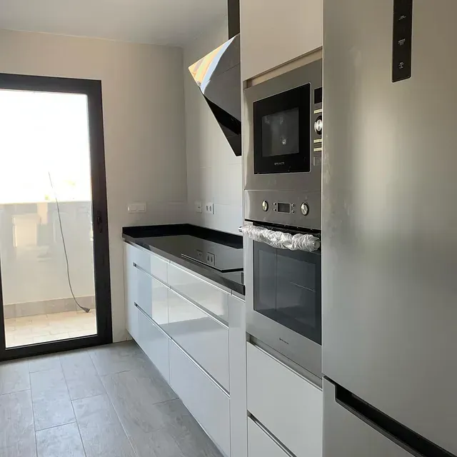 Una cocina con electrodomésticos de acero inoxidable y gabinetes blancos.