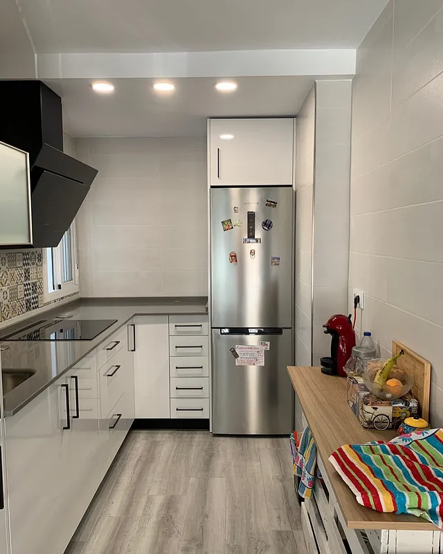 Una cocina con electrodomésticos de acero inoxidable y gabinetes blancos.