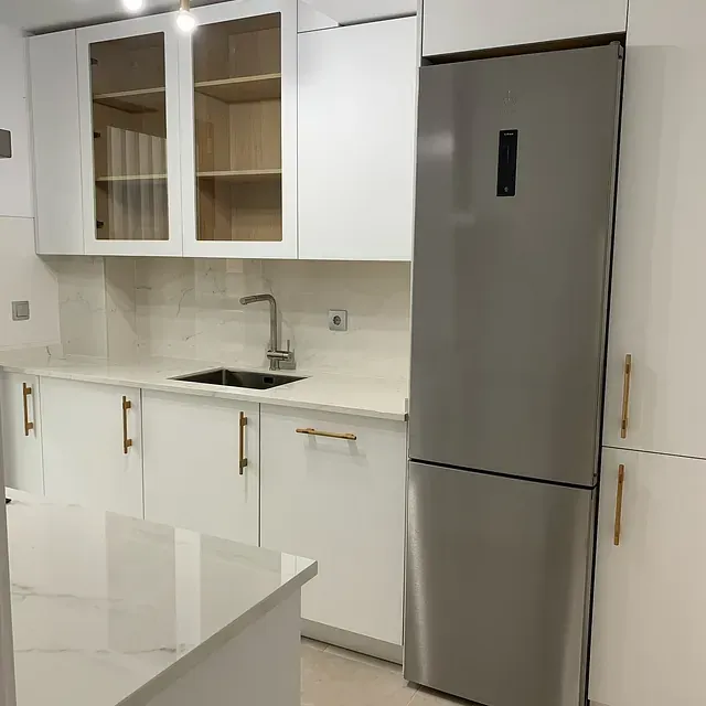 Una cocina con gabinetes blancos y un refrigerador de acero inoxidable.