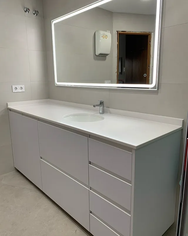 Un baño con lavabo, espejo y cajones.