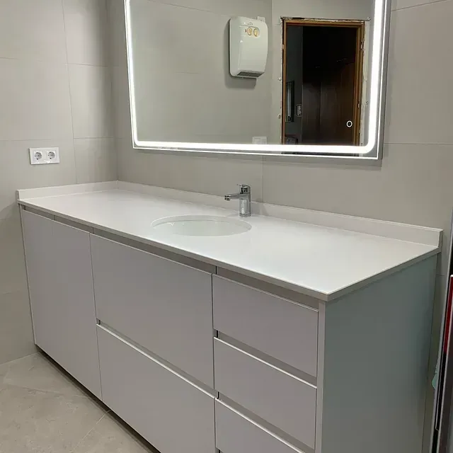 Un baño con lavabo, espejo y cajones.