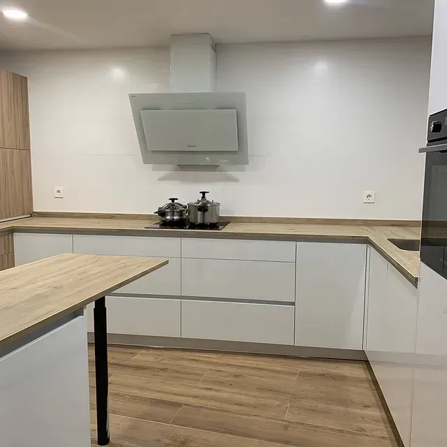 Una cocina con gabinetes blancos y encimeras de madera.