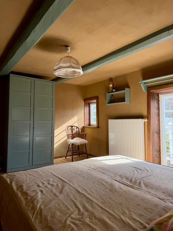 Geräumiges zweites Gästezimmer im Auengut mit großem Doppelbett, stilvoller dunkler Akzentwand und moderner Beleuchtung.