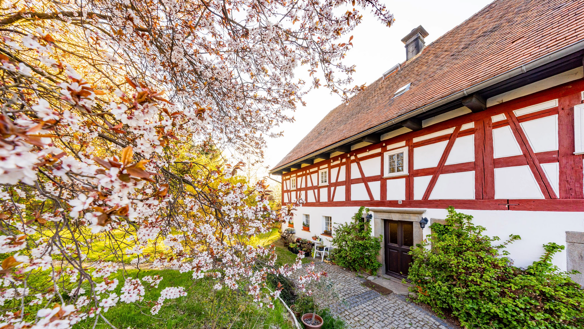 Sonniger Innenhof und Gartenanlage des Auenguts Bertsdorf-Hörnitz, ideal für entspannte Stunden im Freien.