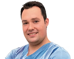 Un hombre con un uniforme azul sonríe para la cámara.