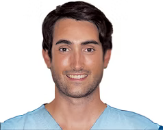 Un hombre con barba viste un uniforme azul y sonríe.