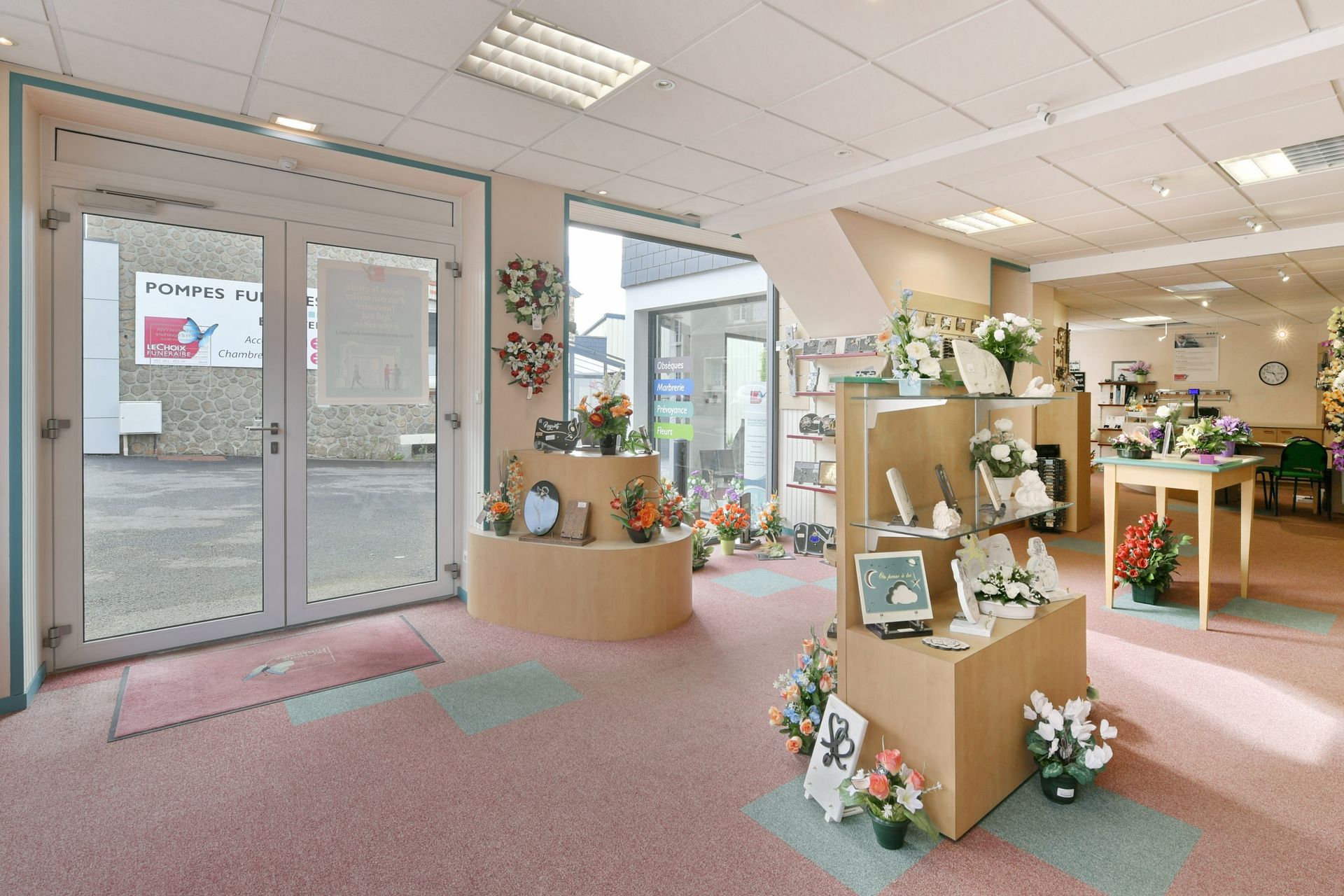 Intérieur des pompes funèbres : exposition de fleurs, plaques et urnes funéraires