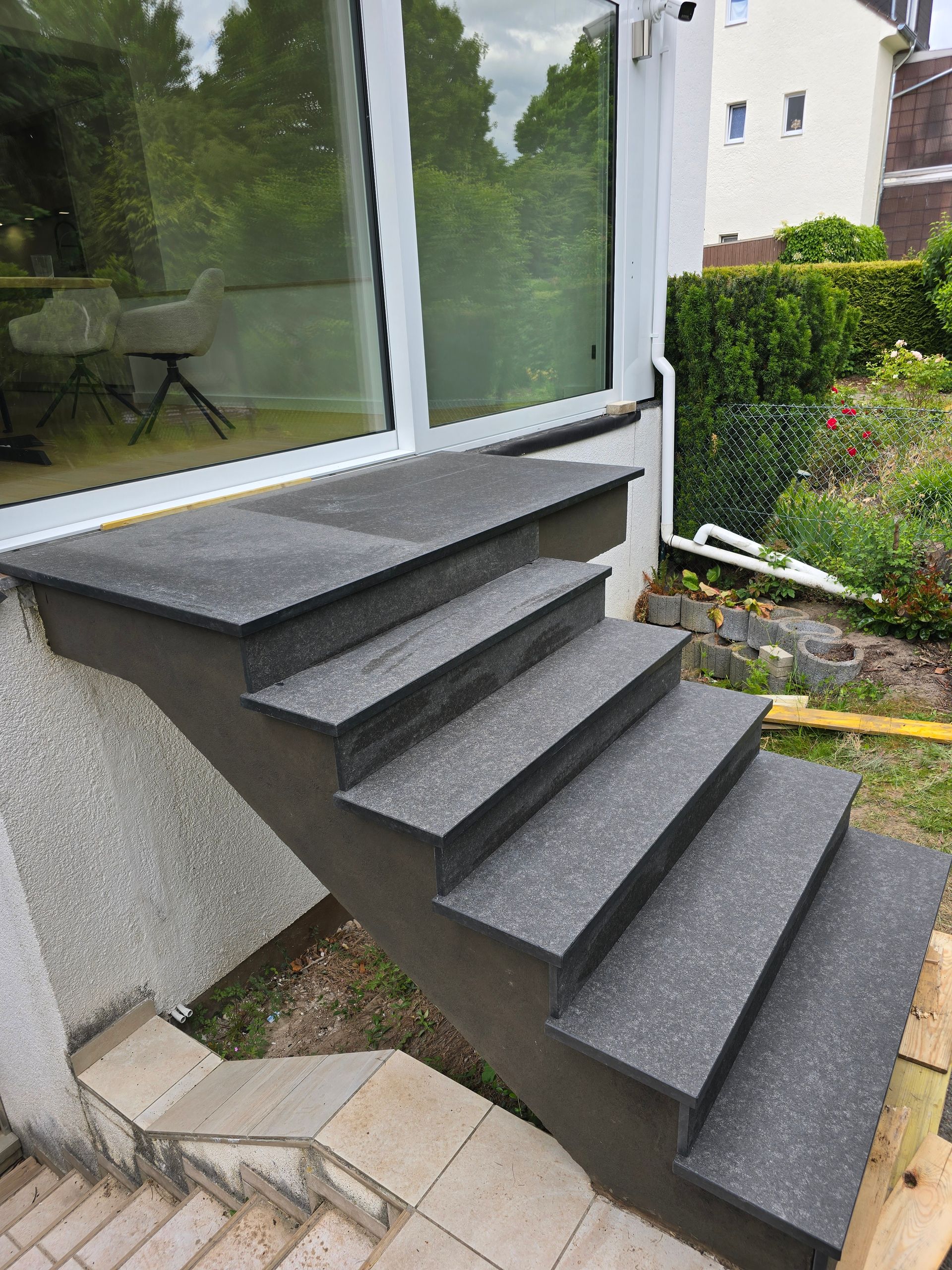 Eine Außentreppe aus Beton führt zu einer Glasschiebetür.