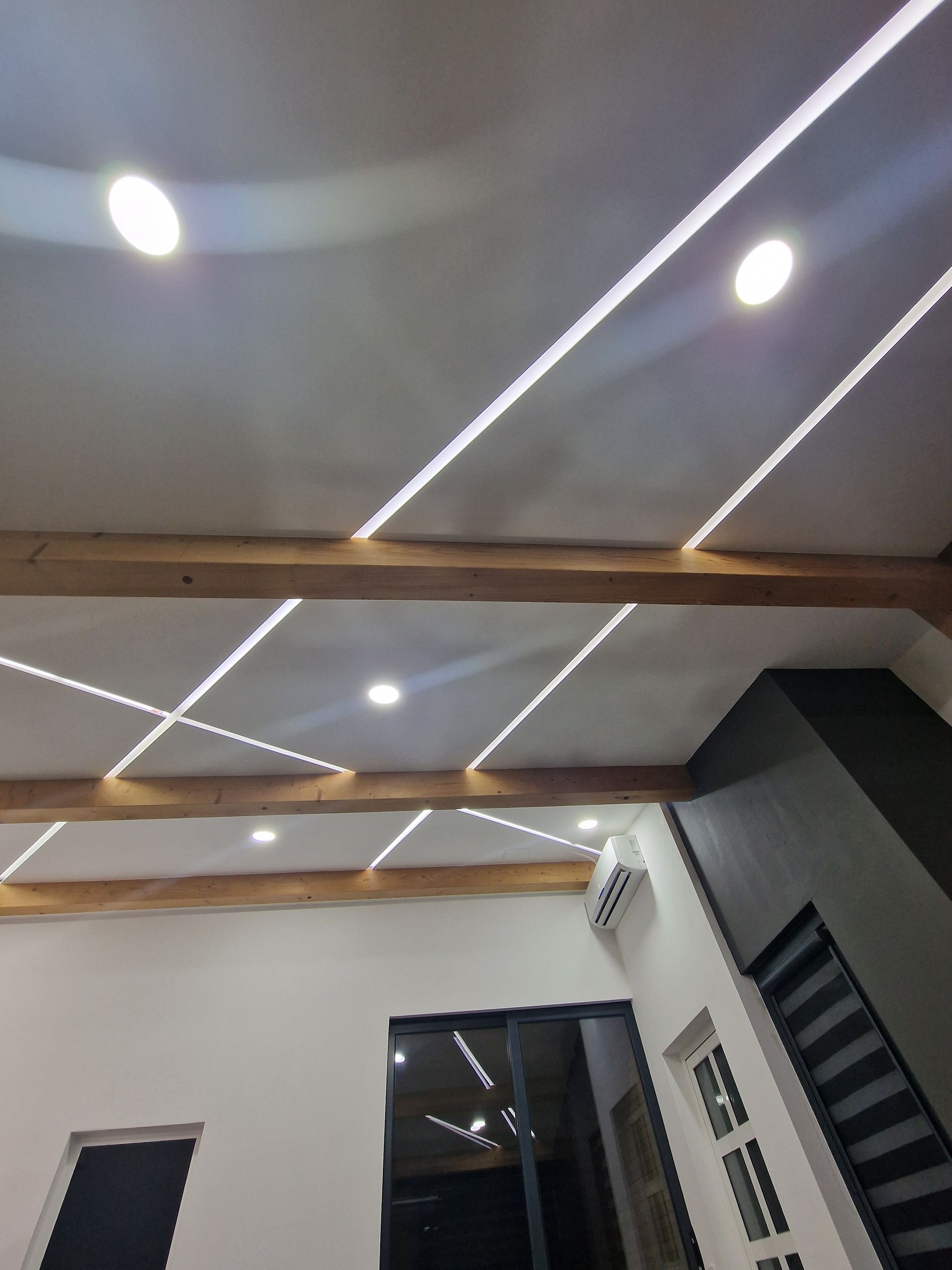 Die Decke im Innenraum ist mit Einbaustrahlern und Holzbalken versehen. Weiße Wände und ein dunkler Türrahmen sind zu sehen.