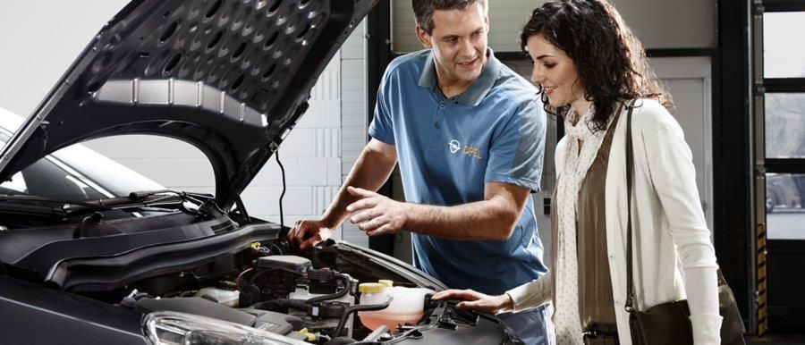 Ein Mann und eine Frau schauen unter die Motorhaube eines Autos.