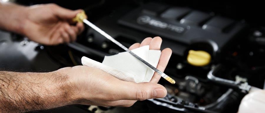 Eine Person prüft den Ölstand eines Autos mit einem Ölmessstab.