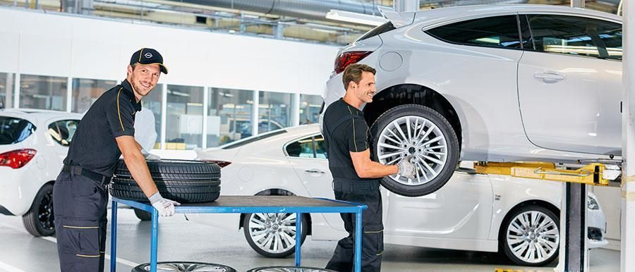 Zwei Männer arbeiten in einer Garage an einem Auto
