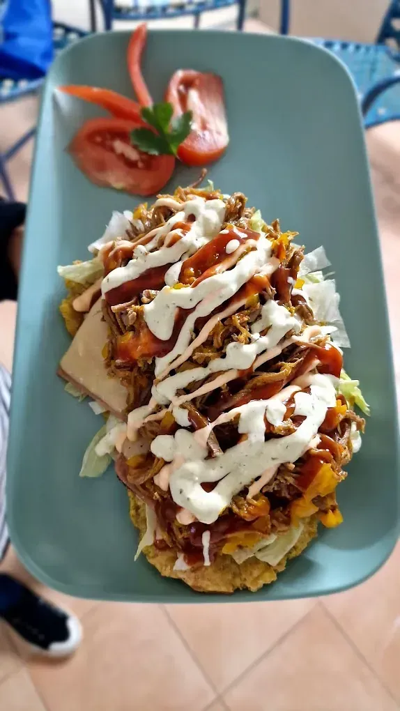 Una persona sostiene un plato de comida con tomates encima.