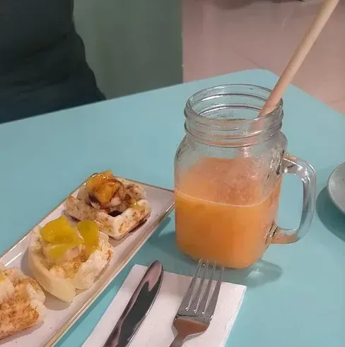 Un tarro de cristal con zumo de naranja junto a un plato de comida.