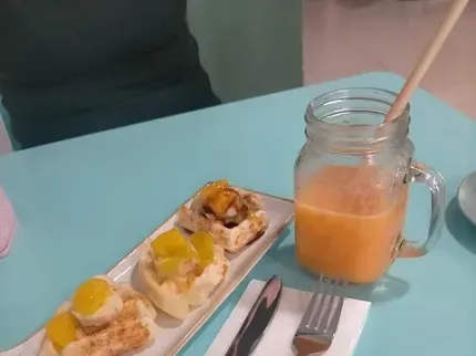 Un plato de comida y un tarro de cristal con zumo de naranja sobre una mesa.