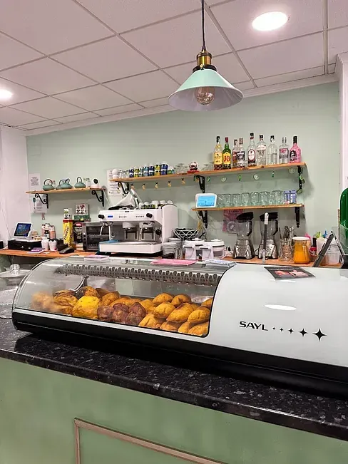 Una cocina con una vitrina llena de comida y una máquina de café.