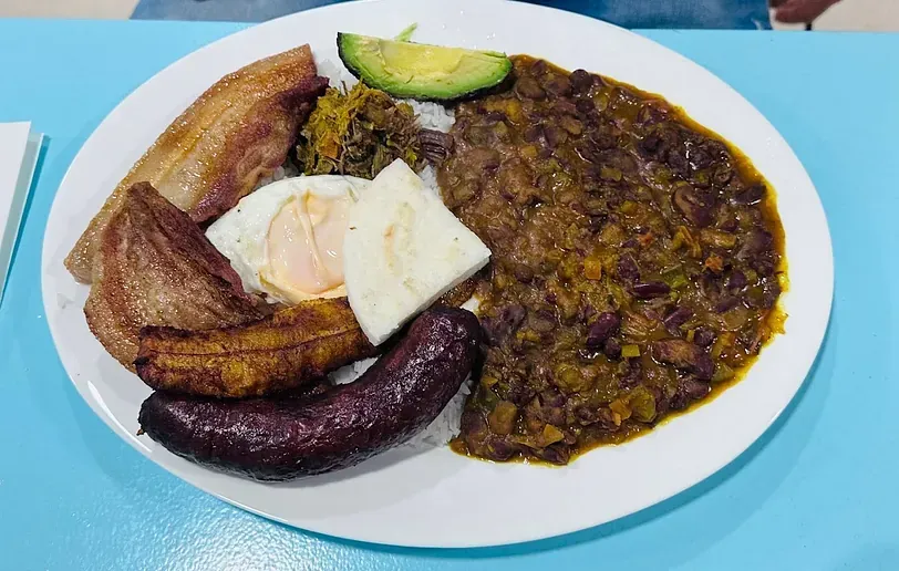 Un plato blanco cubierto con una variedad de alimentos sobre una mesa azul.