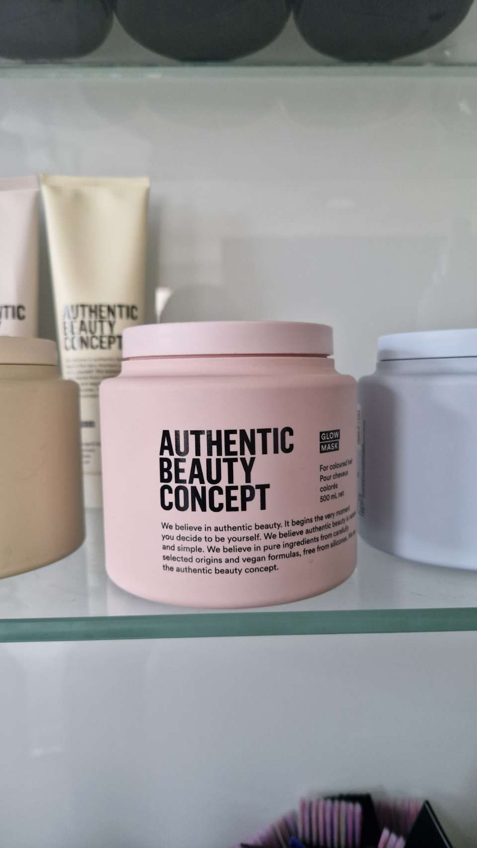 Un pot de concept de beauté authentique est posé sur une étagère en verre.