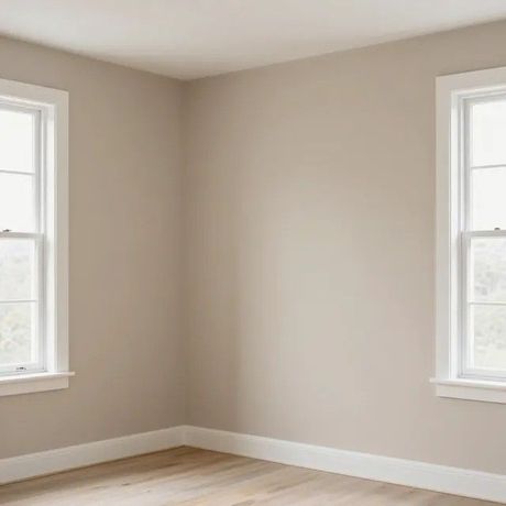 Habitación esquinera vacía de color beige con dos ventanas y suelo de madera clara.
