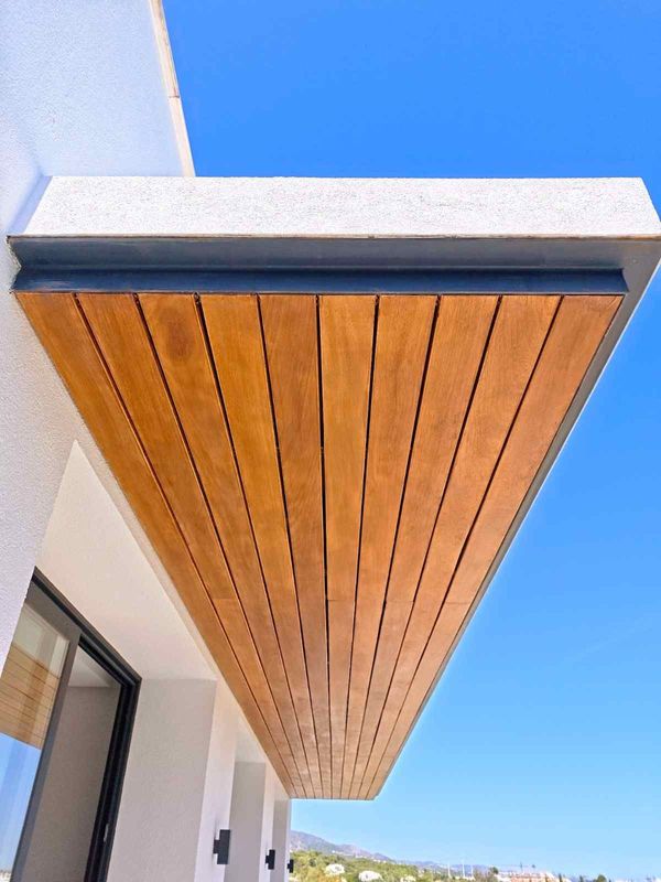 Balcón con paneles de madera bajo un cielo azul brillante