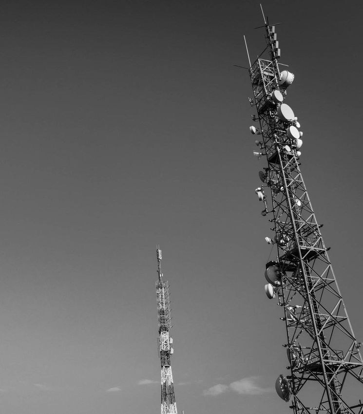 Una fotografía en blanco y negro de dos torres telefónicas contra un cielo azul.