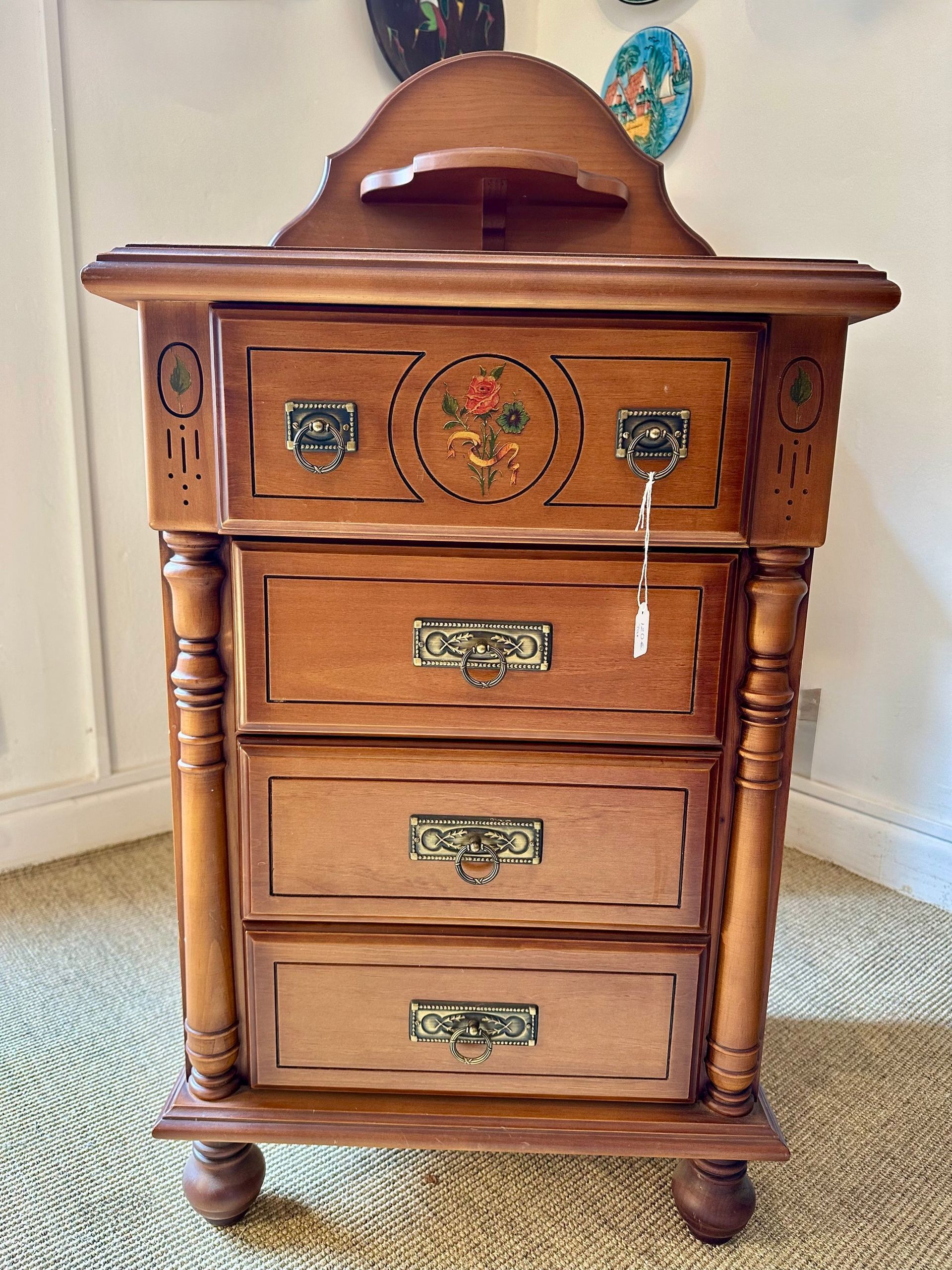 Mesita de noche antigua de madera con cajones, detalle floral y enchufes eléctricos.