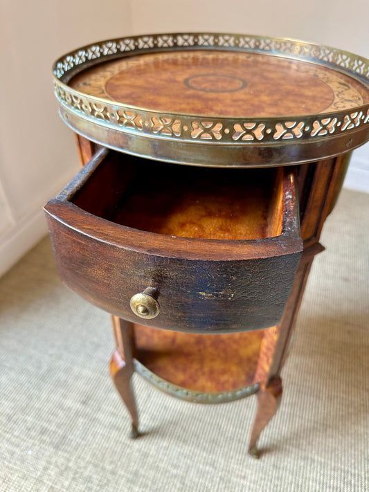 Mesita de noche con cajón abierto, detalles en madera y latón.