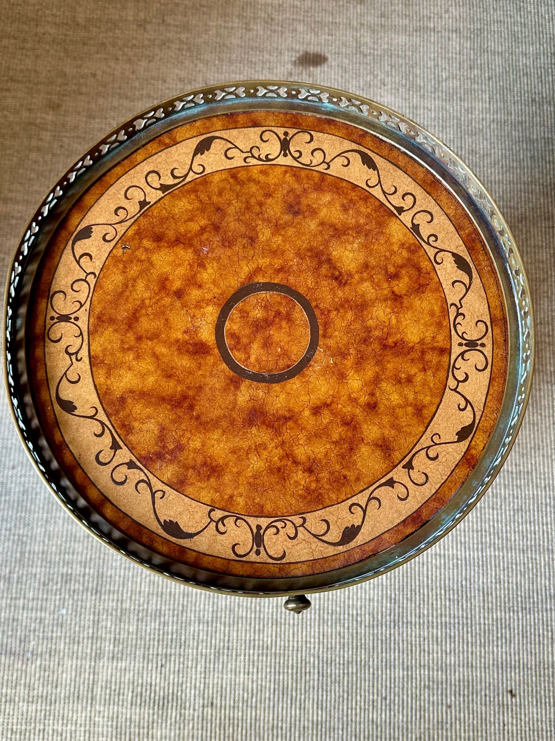 Mesa redonda con superficie decorativa en tonos cálidos y borde de metal.