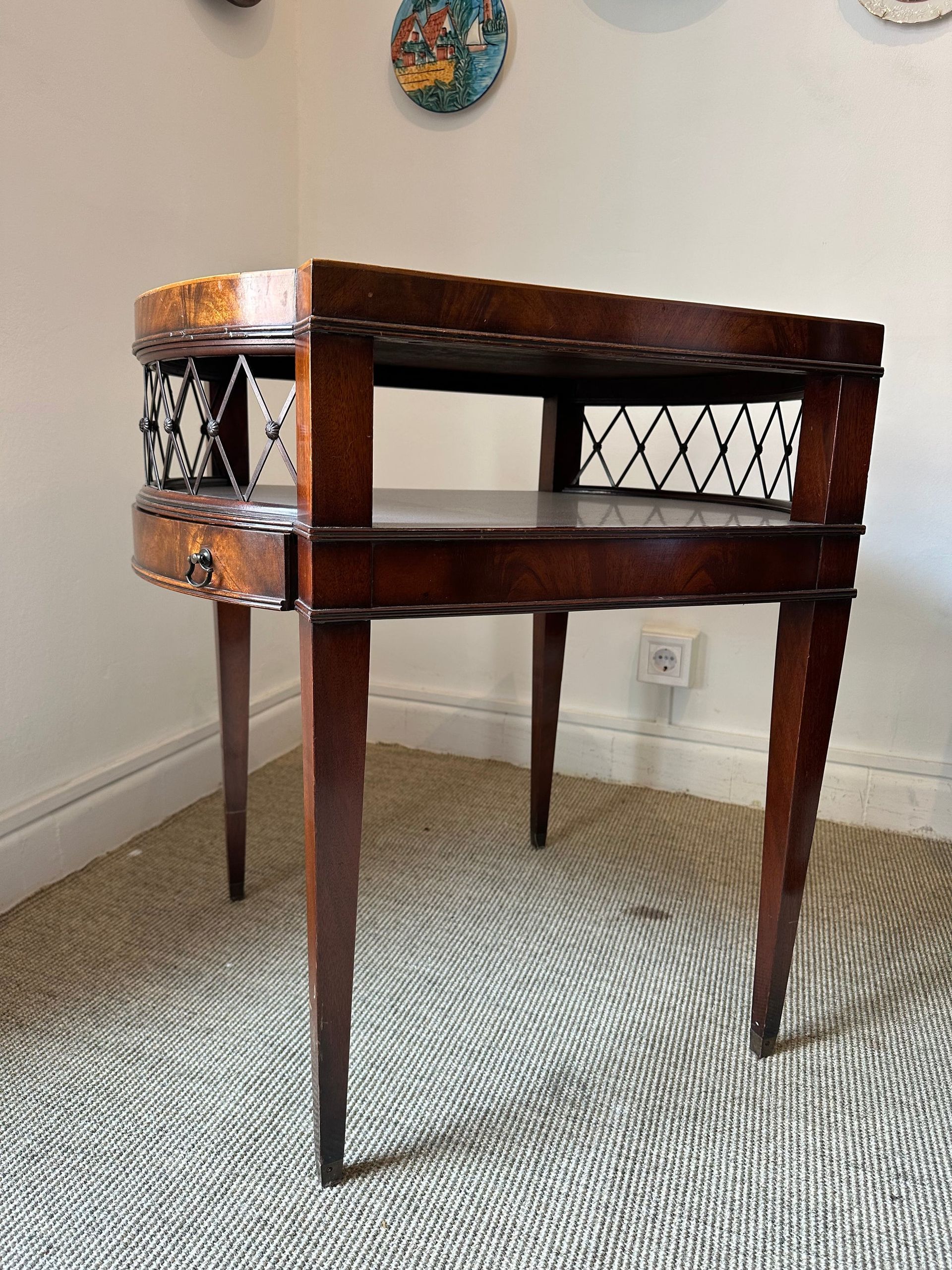 Mesa auxiliar antigua de color marrón con cajón y detalles enrejados.