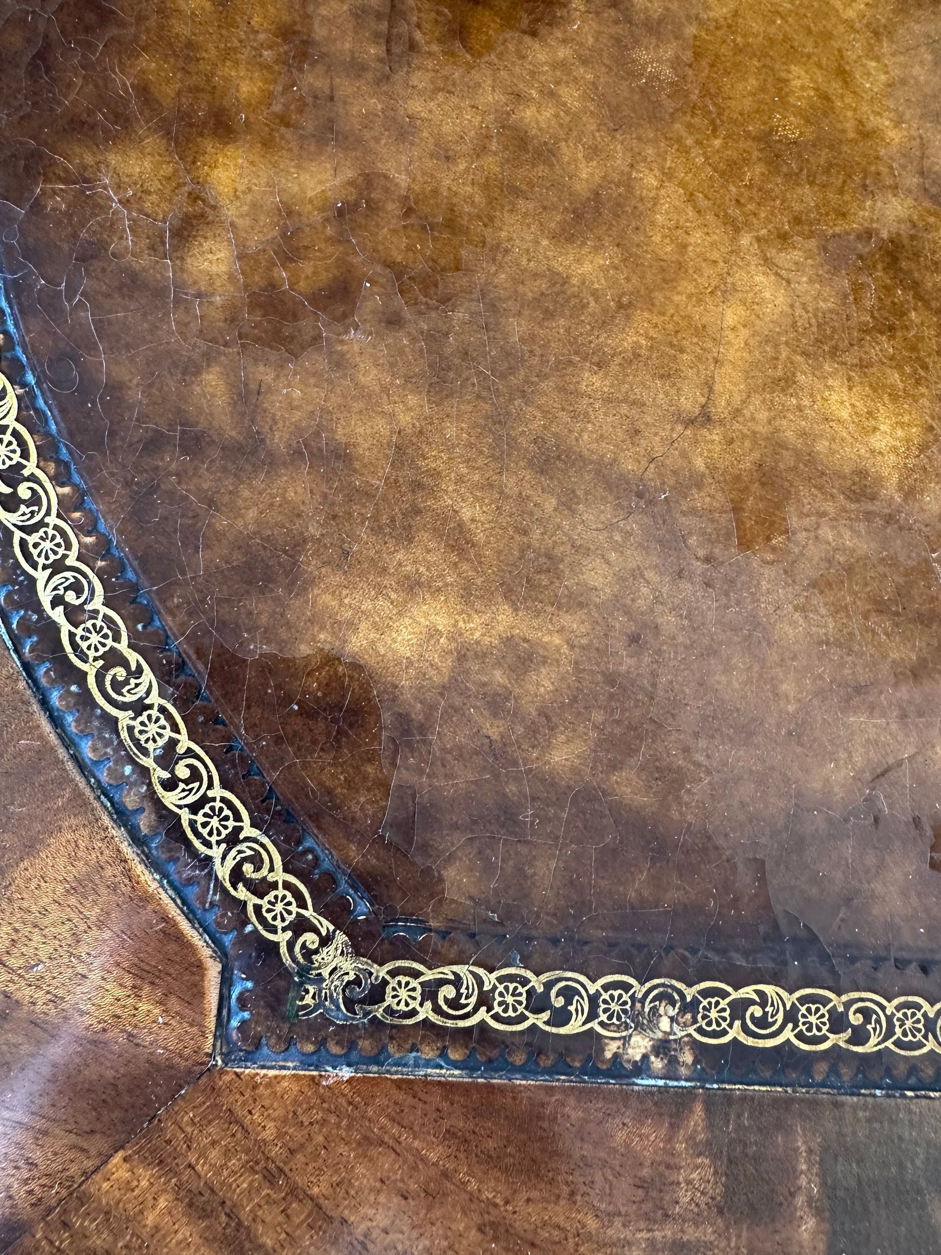 Primer plano de una superficie de cuero marrón con detalles decorativos en dorado y negro.