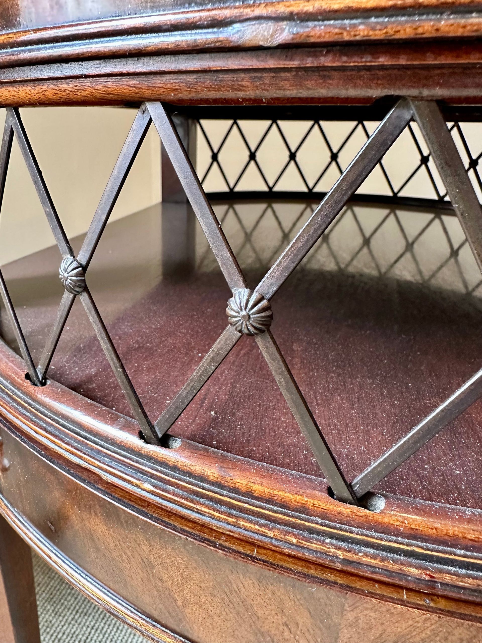 Primer plano de una mesa de madera con detalles ornamentados de hierro en forma de diamante.