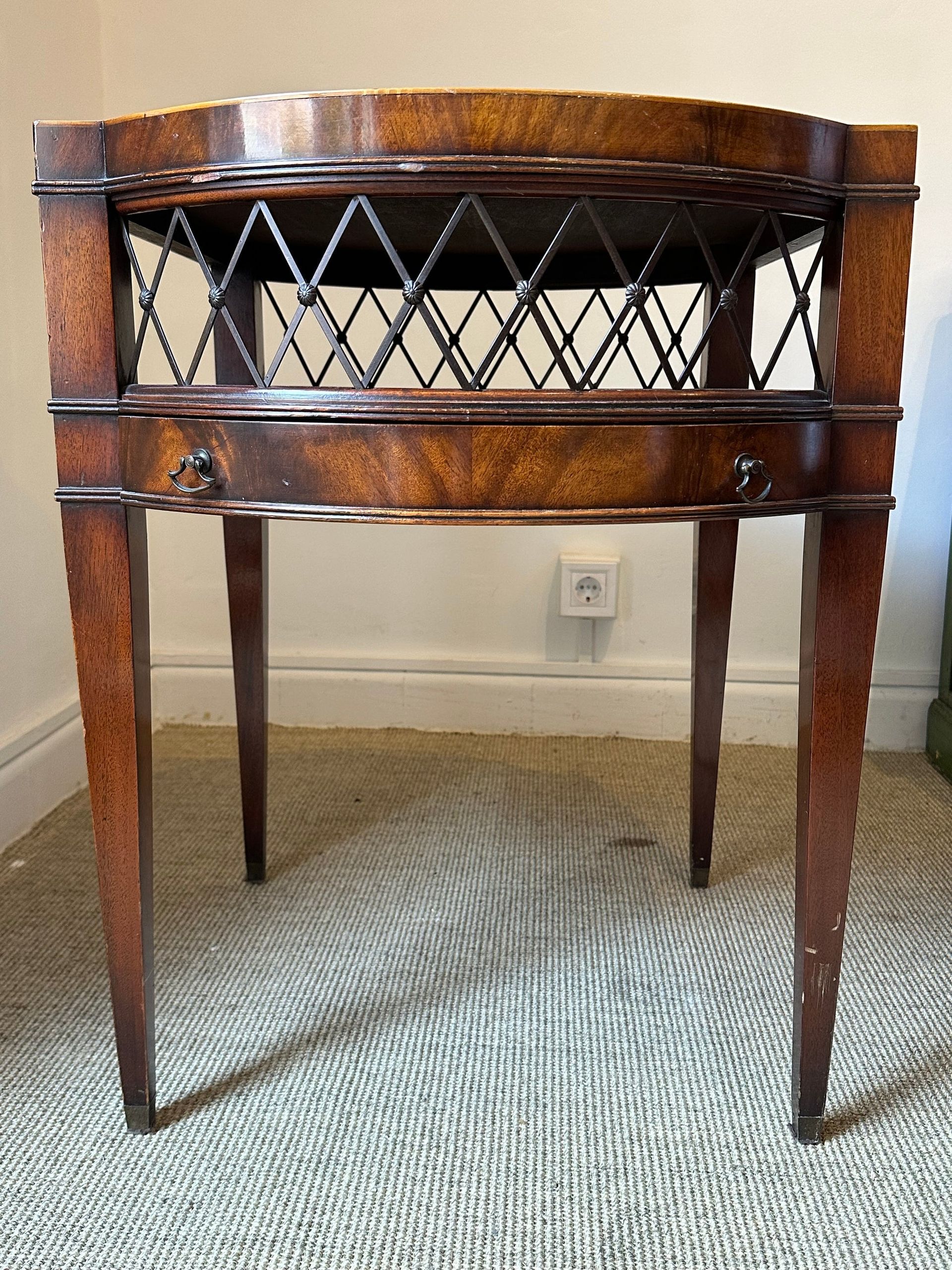 Mesa auxiliar antigua de madera con frente de celosía decorativa y patas delgadas.