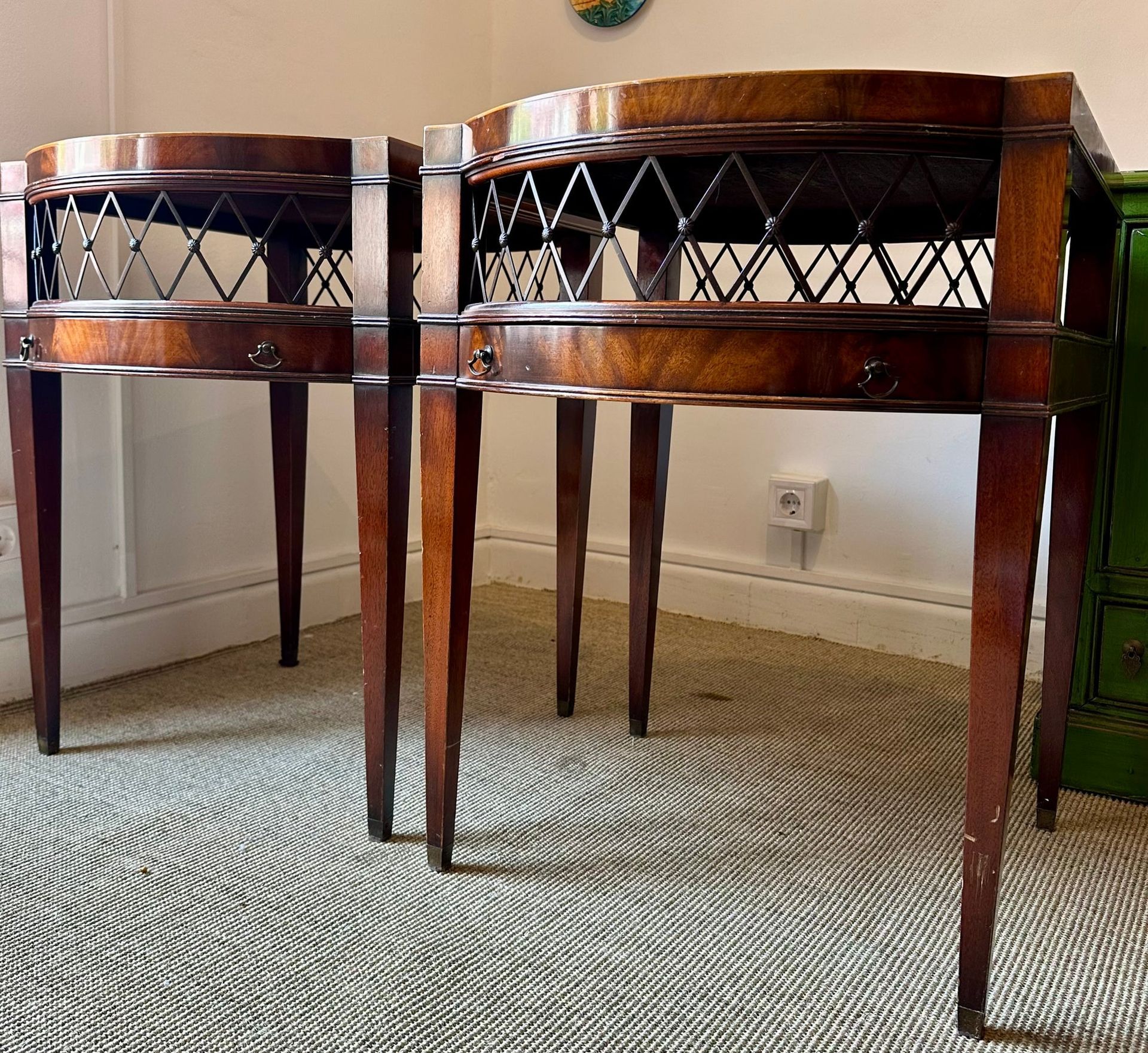 Dos mesitas de noche antiguas de madera oscura con celosía y patas delgadas.