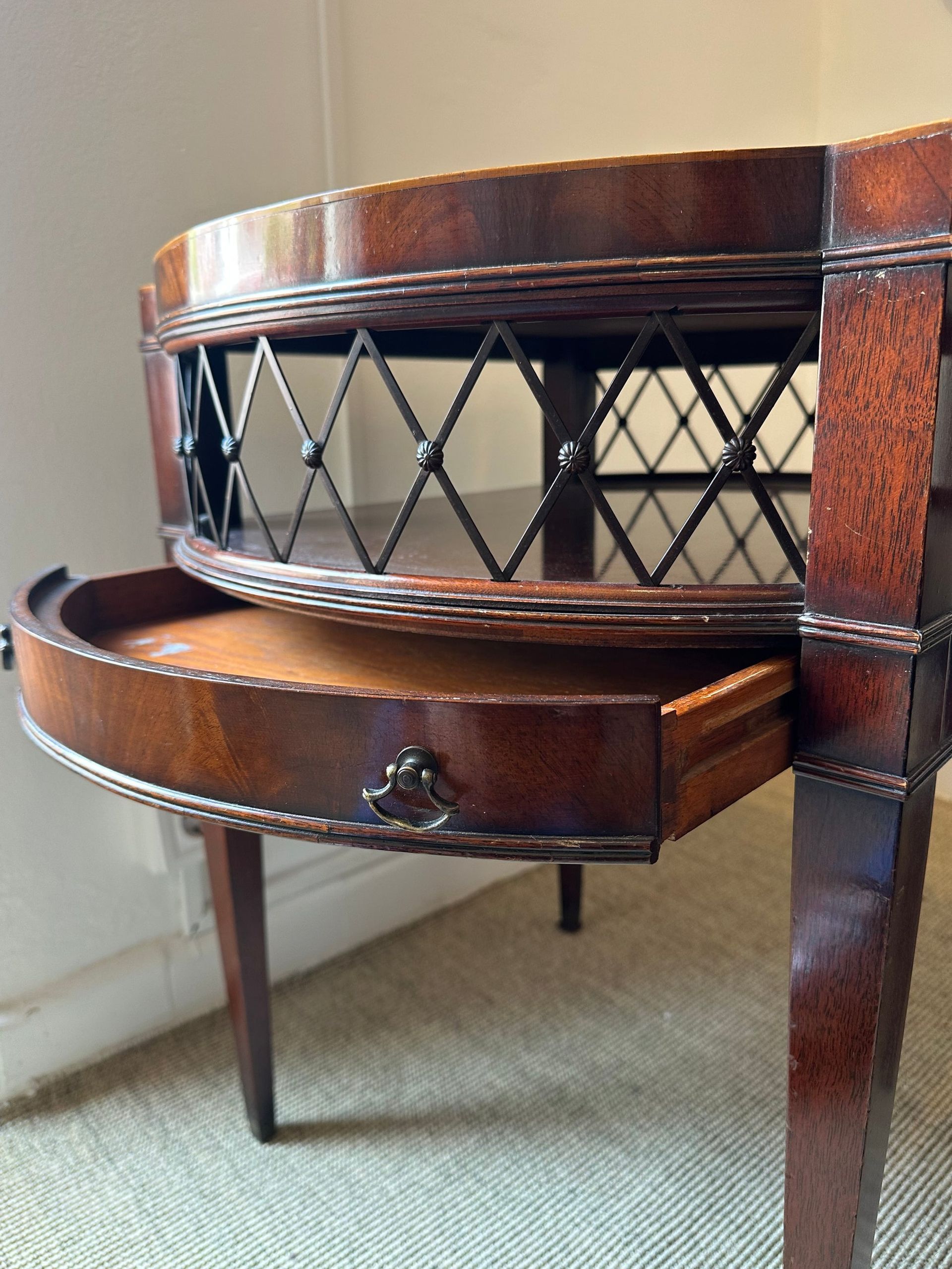 Mesa auxiliar de madera con cajón abierto, con celosía con diseño de rombos y patas estriadas.