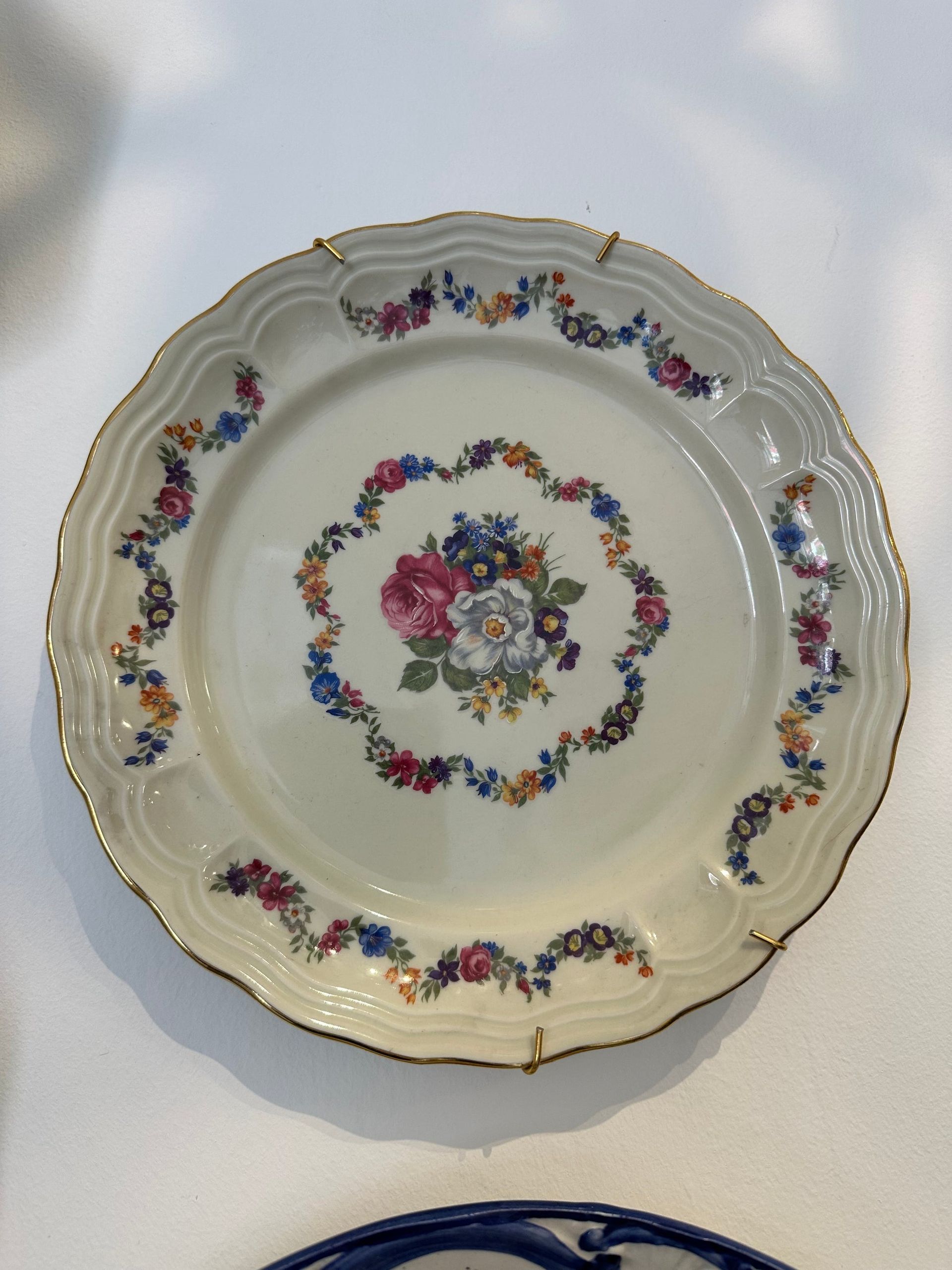 Plato de porcelana ornamentado con diseño floral y ribete dorado.