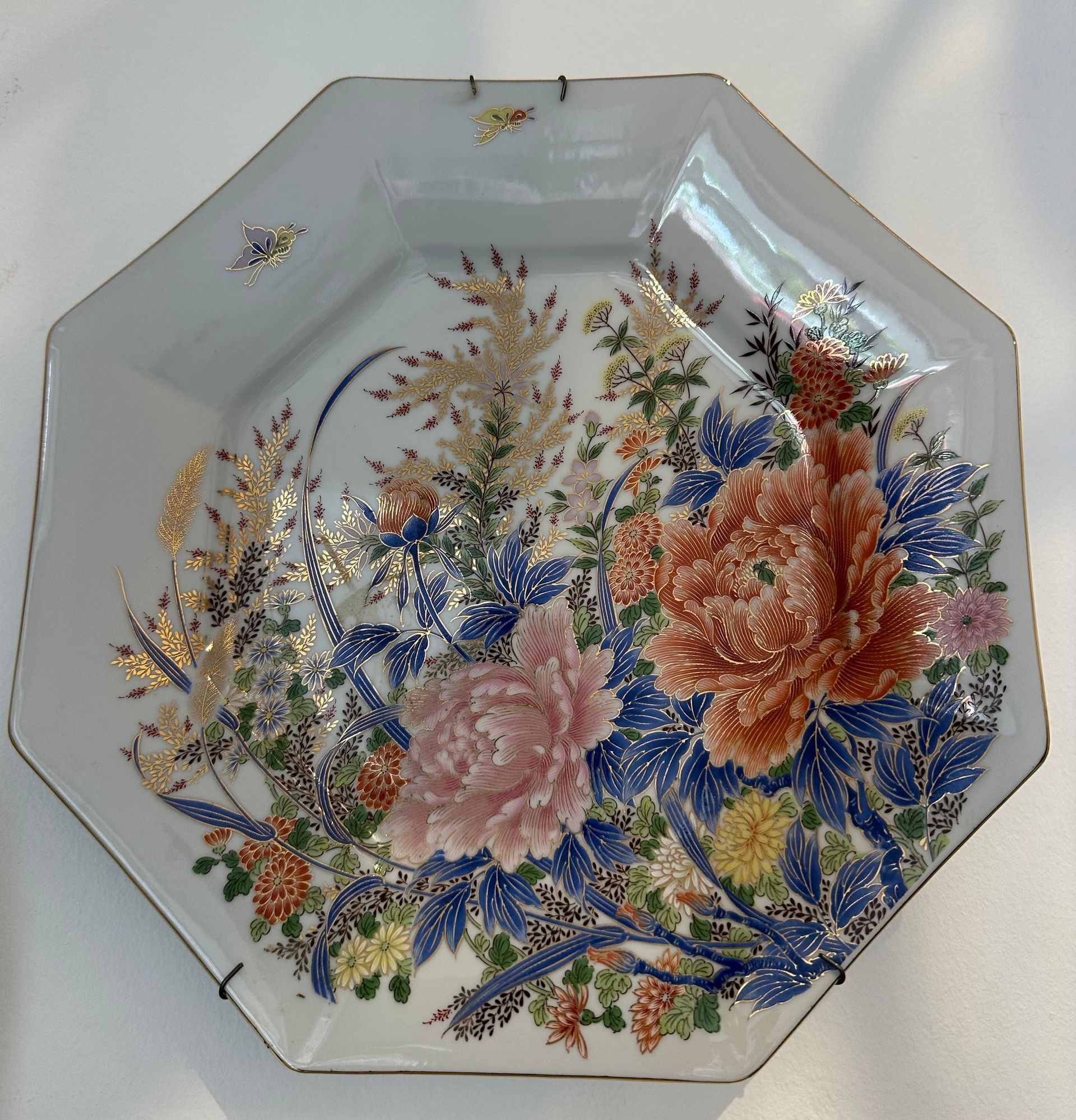 Plato octogonal de porcelana blanca con diseño floral en tonos rosa, naranja, azul y dorado.