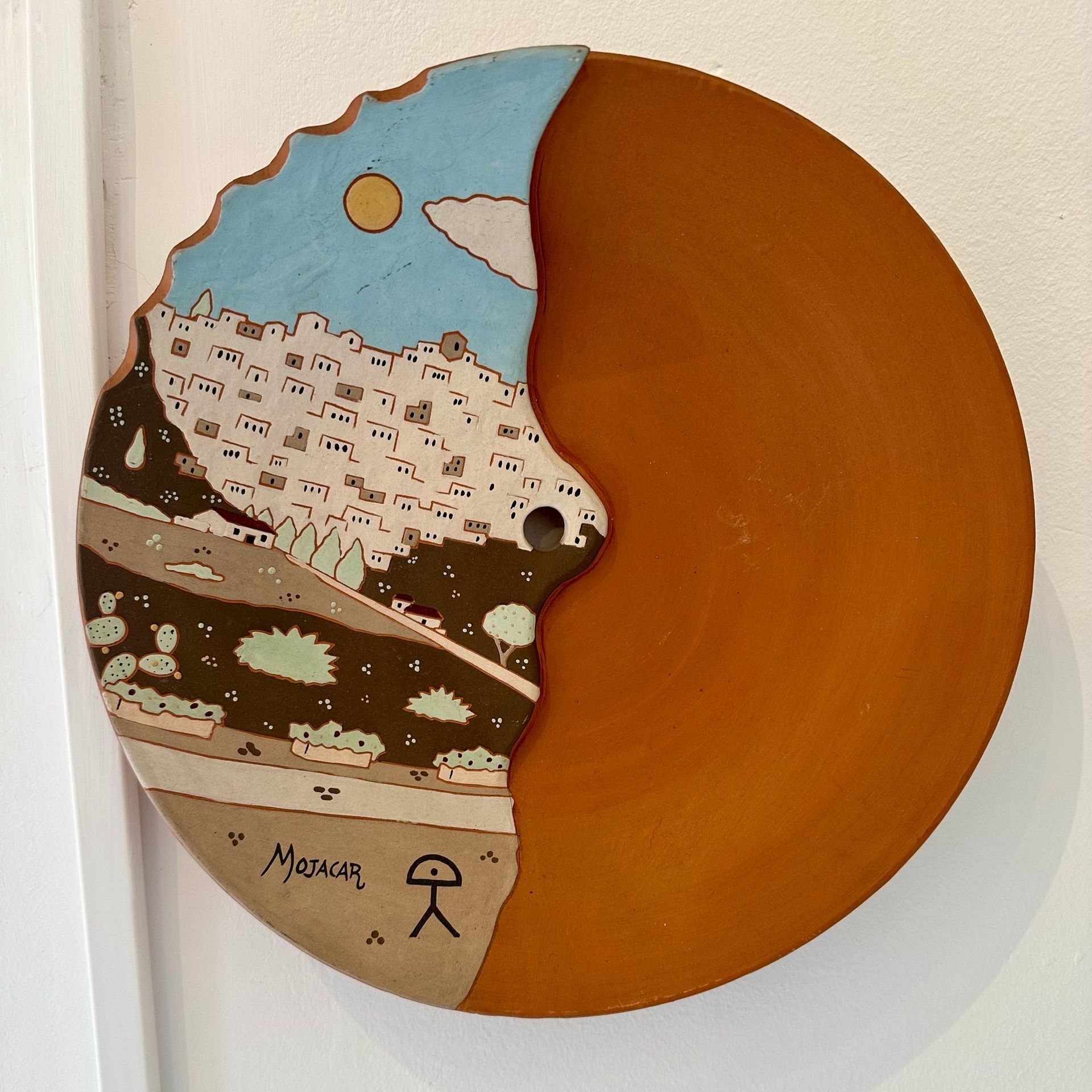 Plato de cerámica artística con paisaje pintado y mitad esmaltada en marrón.