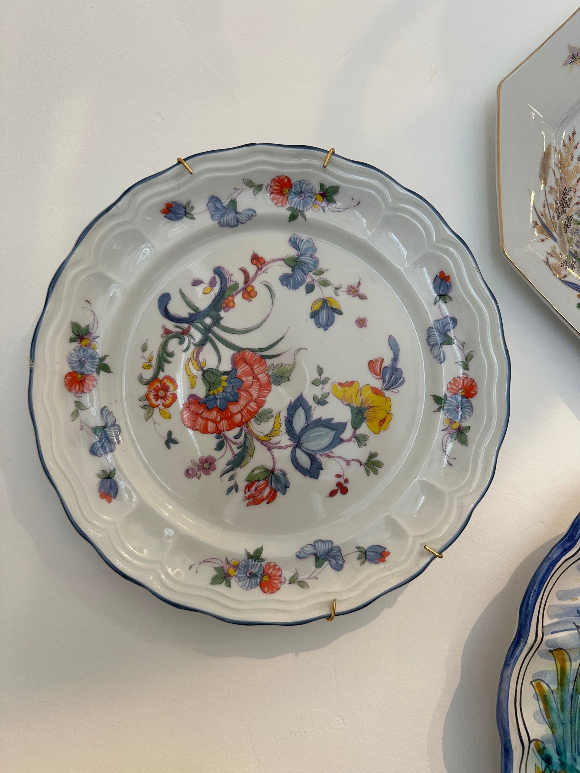 Plato decorativo blanco con diseño floral, borde y borde de color azul.