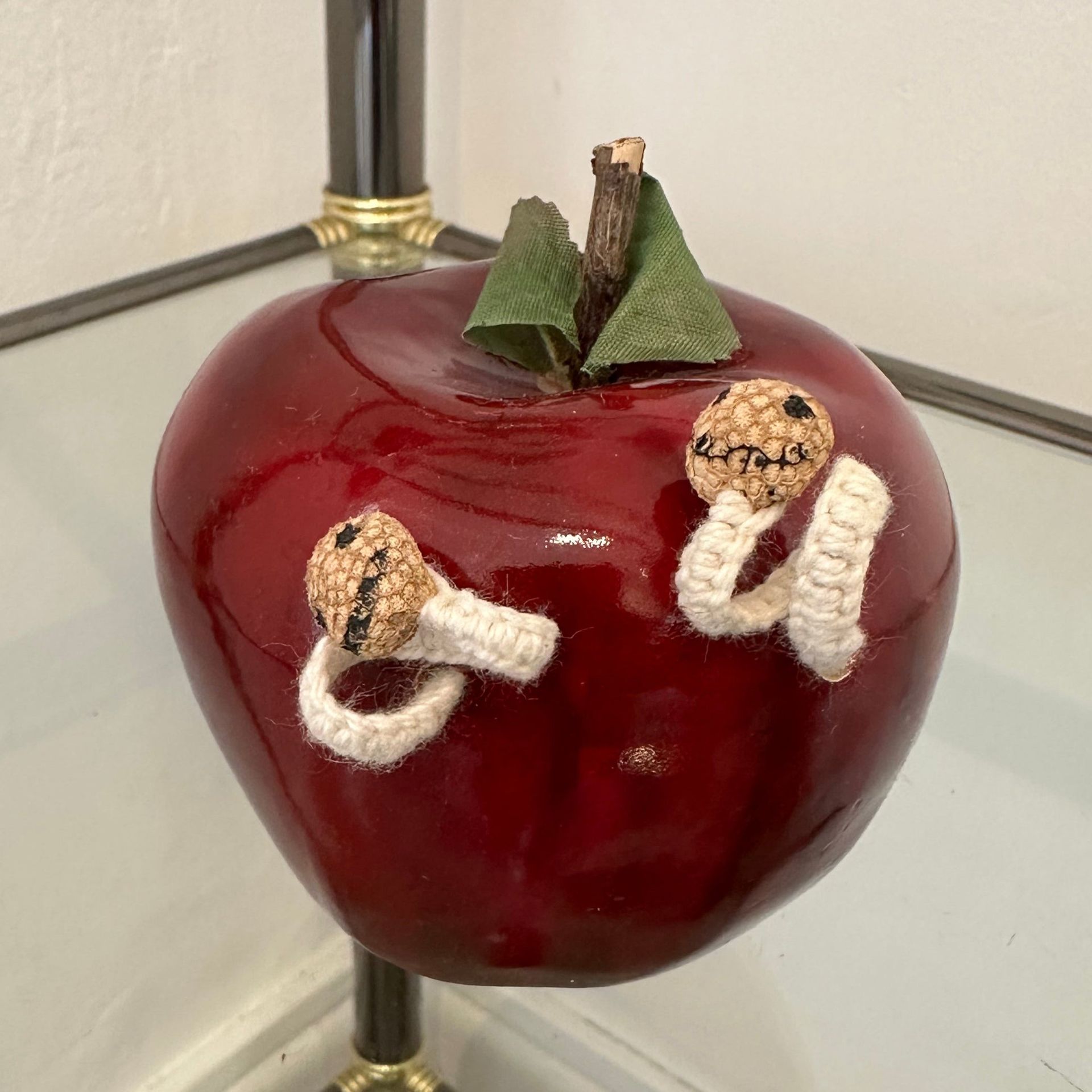 Decoración de manzana roja con dos figuras de gusanos sonrientes.