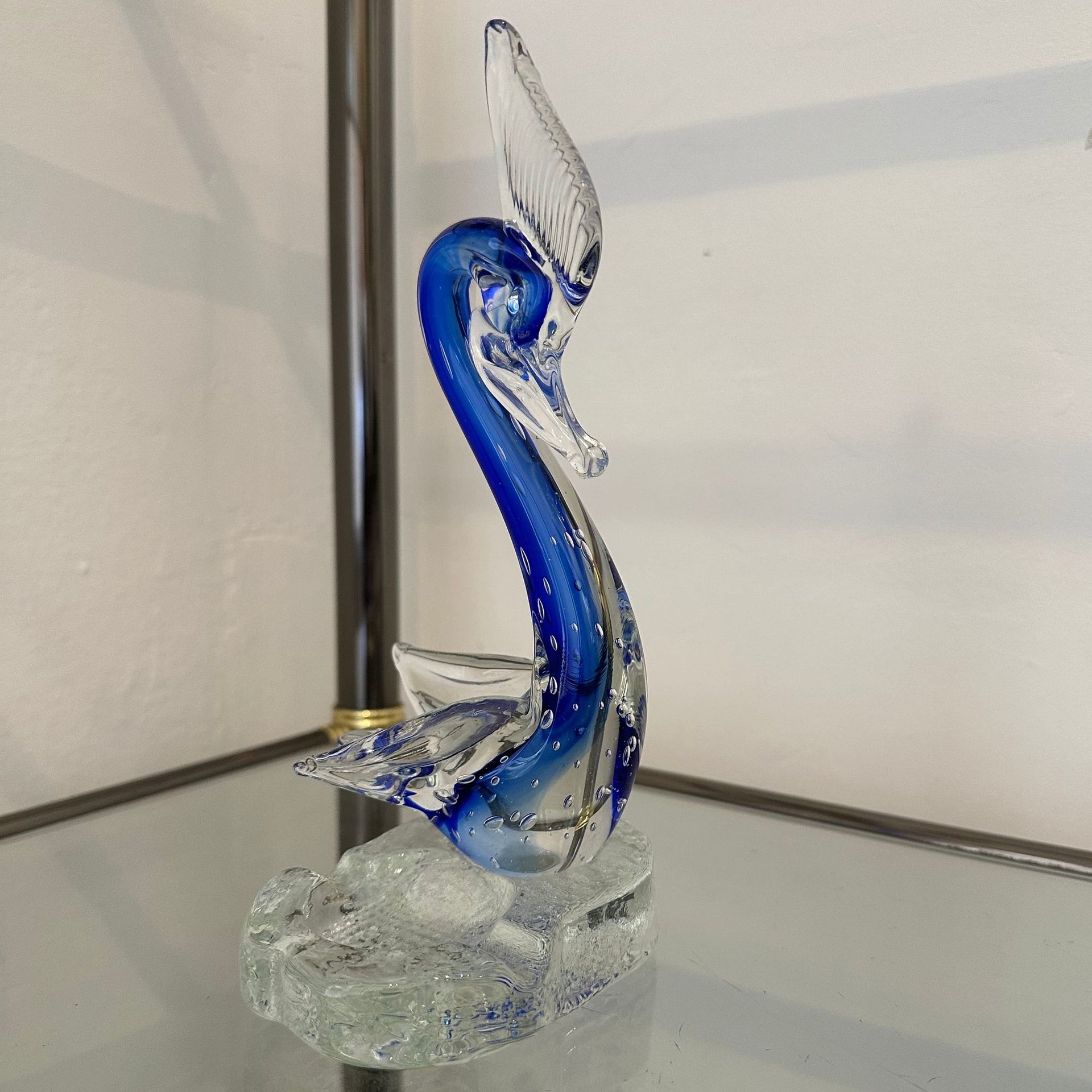 Figura de cisne de cristal azul sobre estante de cristal.