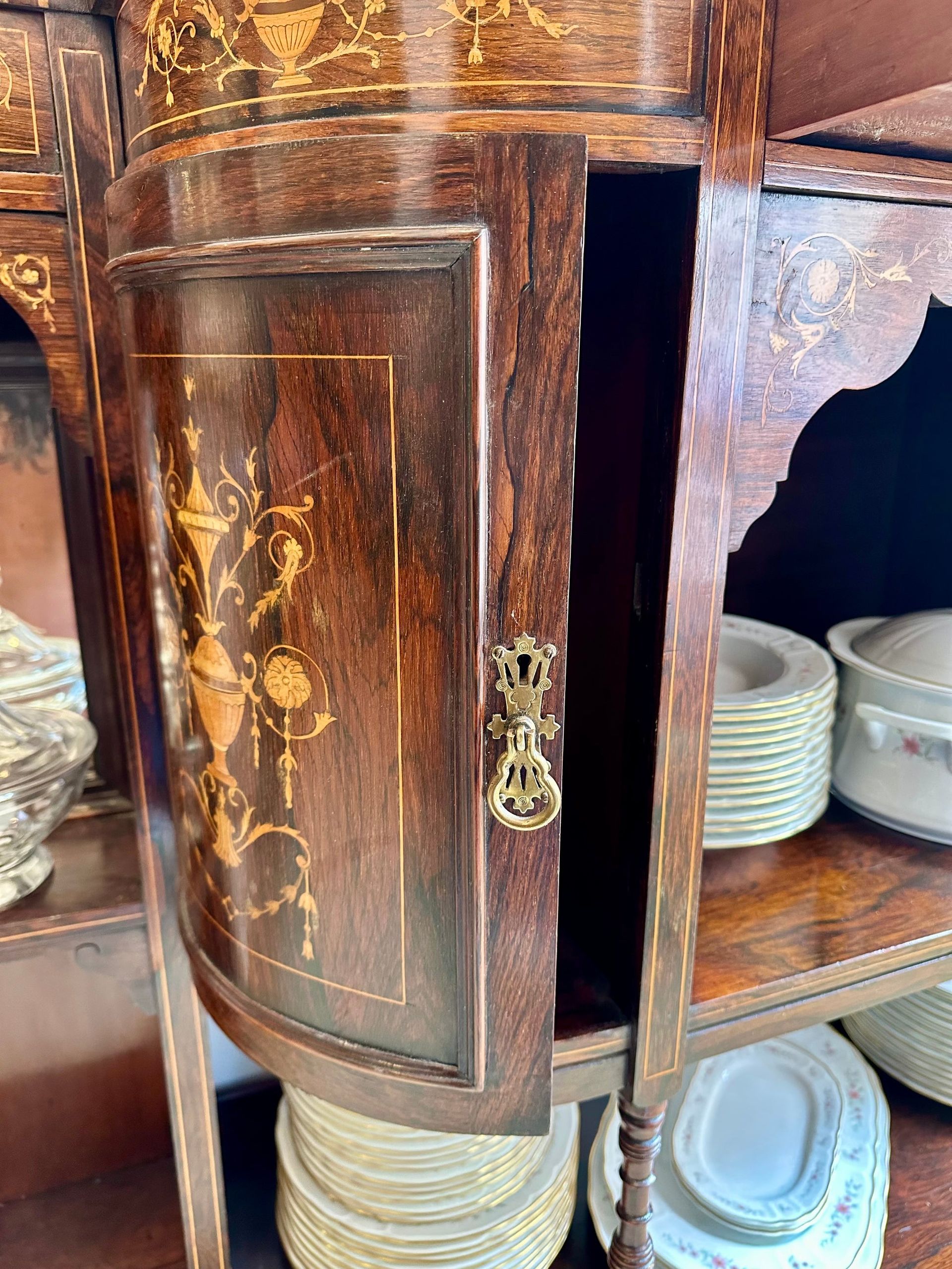 Mueble de madera con puerta abierta, diseño con marquetería, placas apiladas visibles.