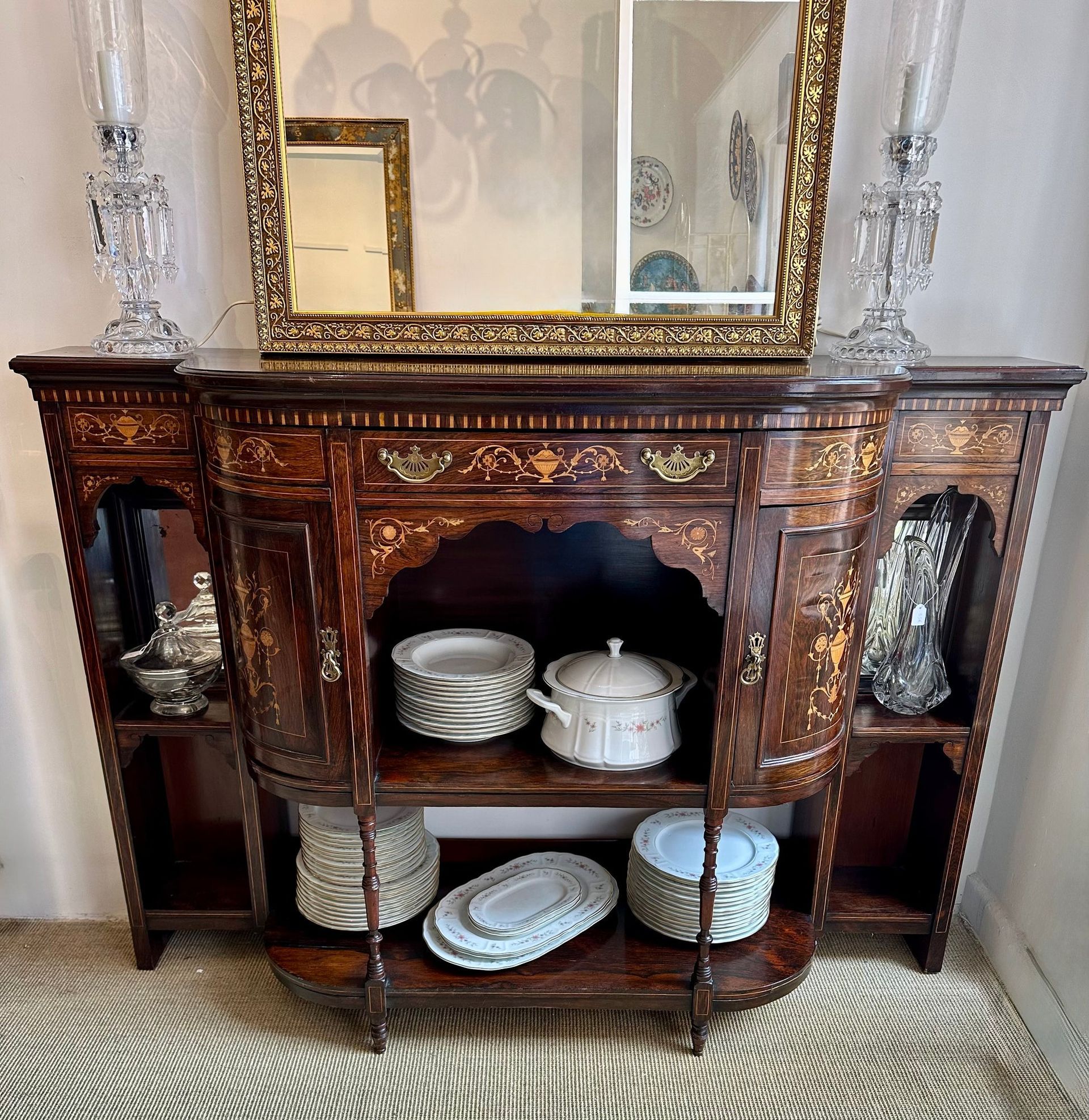 Mueble de madera ornamentado con espejo y cristalería, que contiene platos.