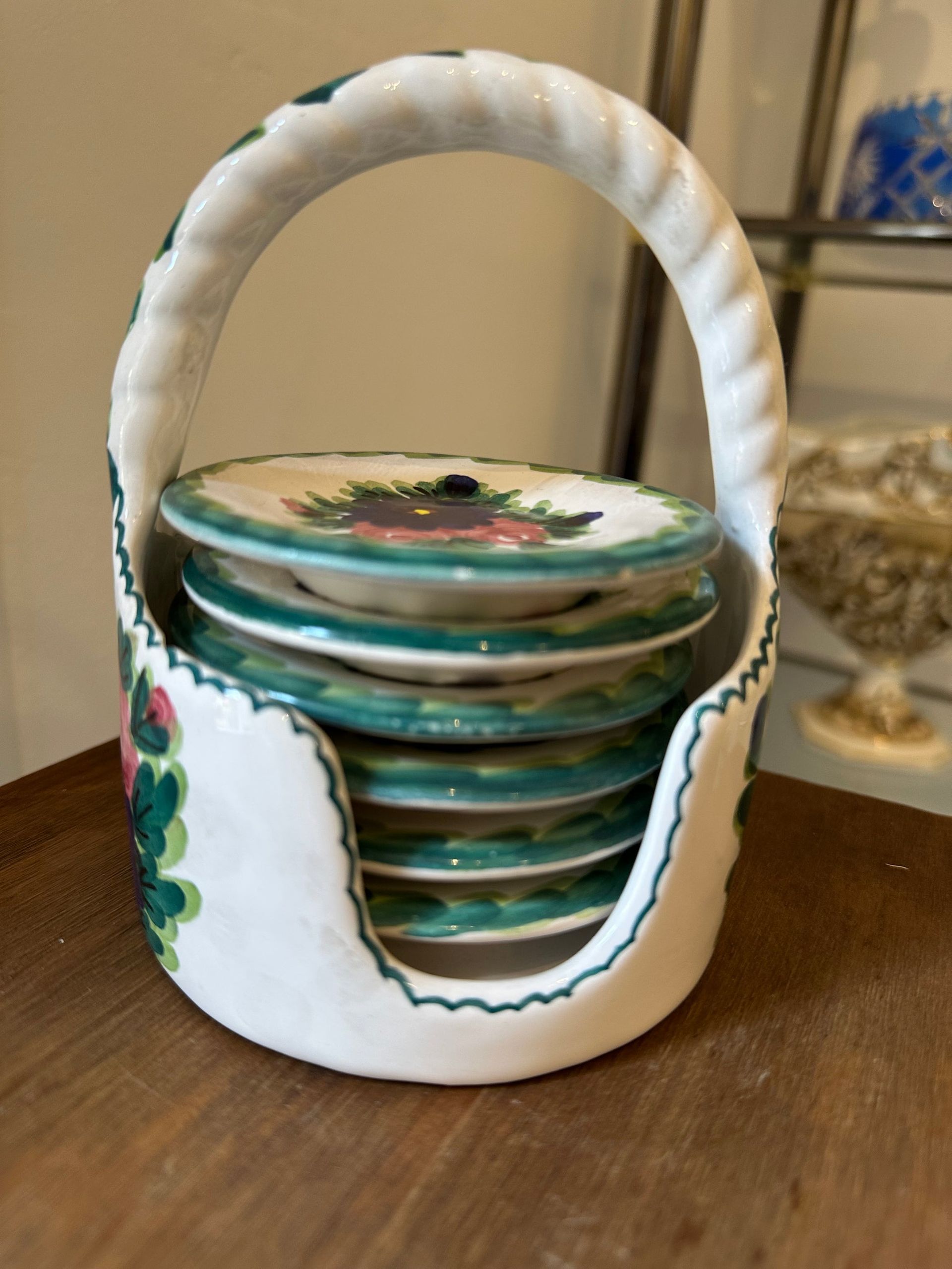 Cesta de cerámica blanca que contiene una pila de pequeños platos florales.