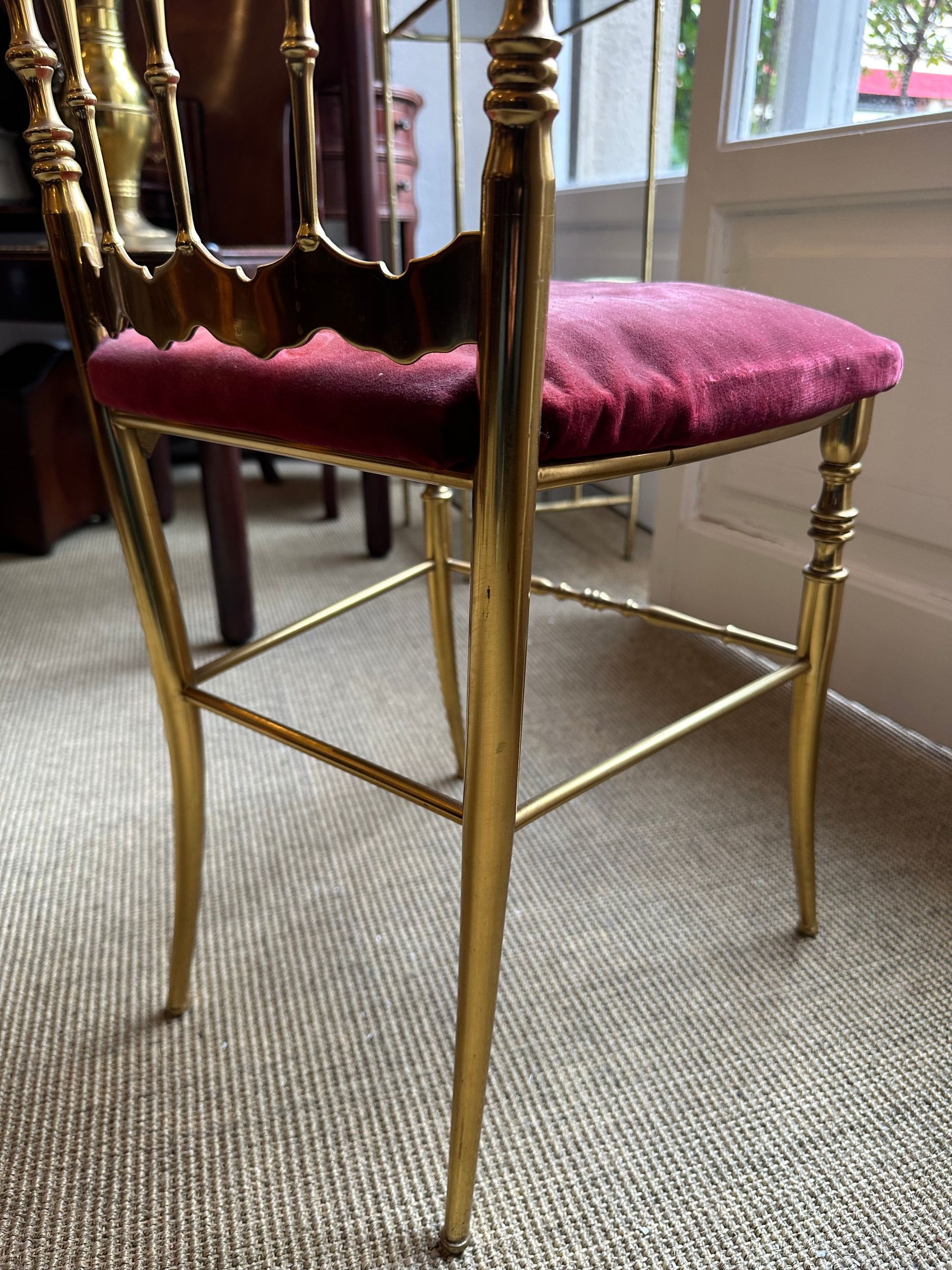 Silla de latón con asiento de terciopelo burdeos, en el interior, primer plano.