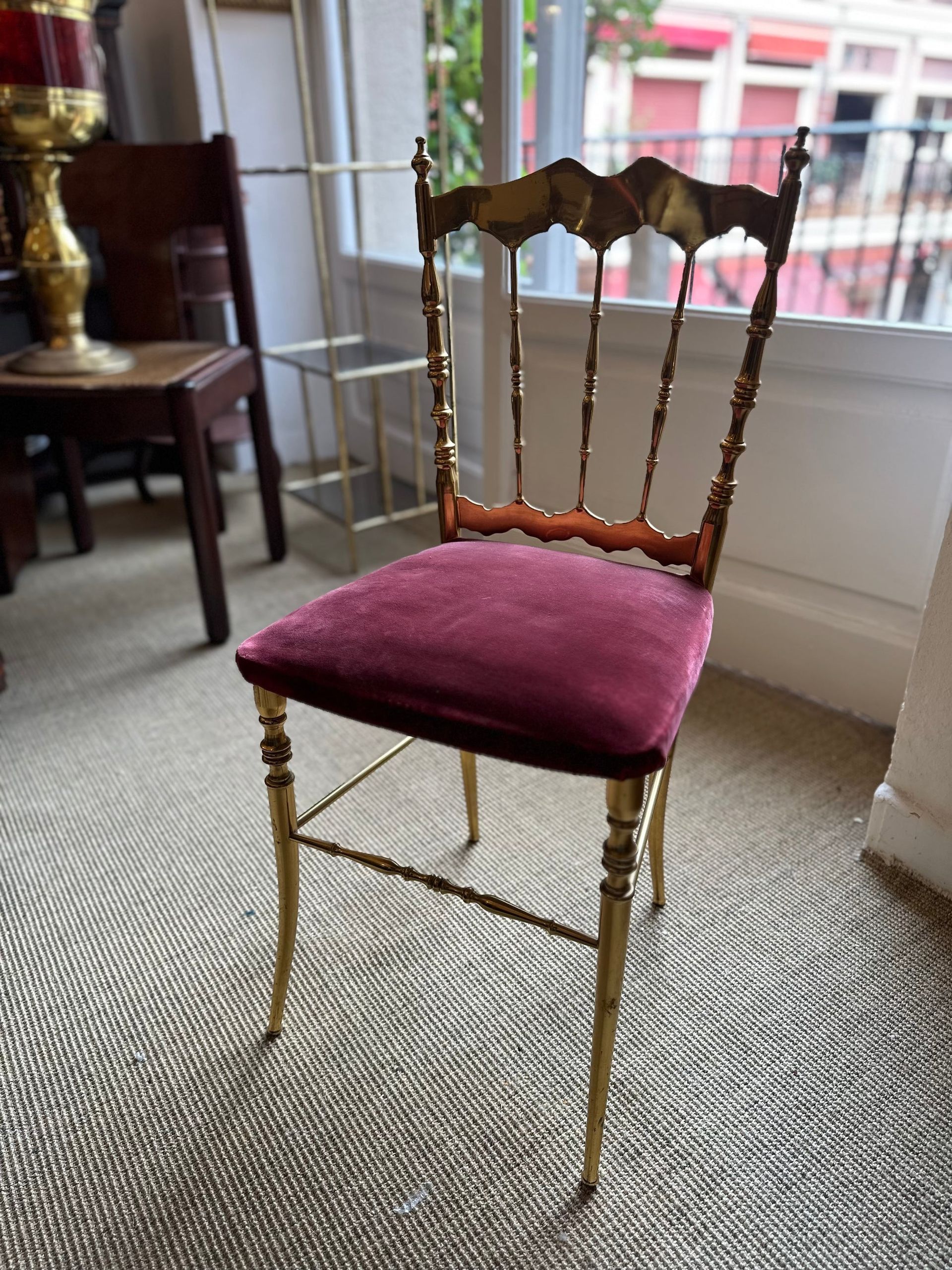 Silla dorada con asiento de terciopelo rojo, frente a una ventana.