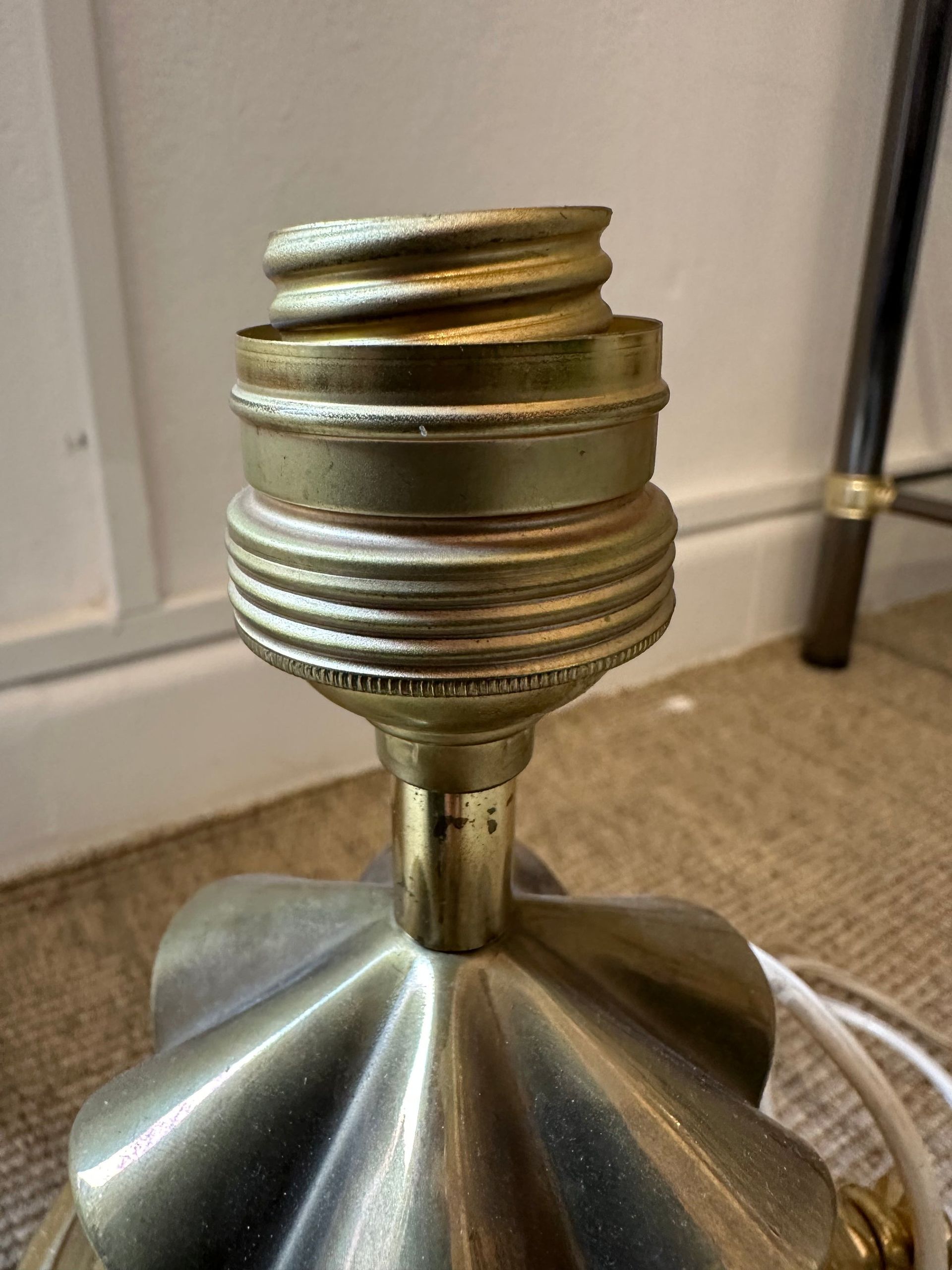 Primer plano de una base de lámpara dorada con un portalámparas vacío.